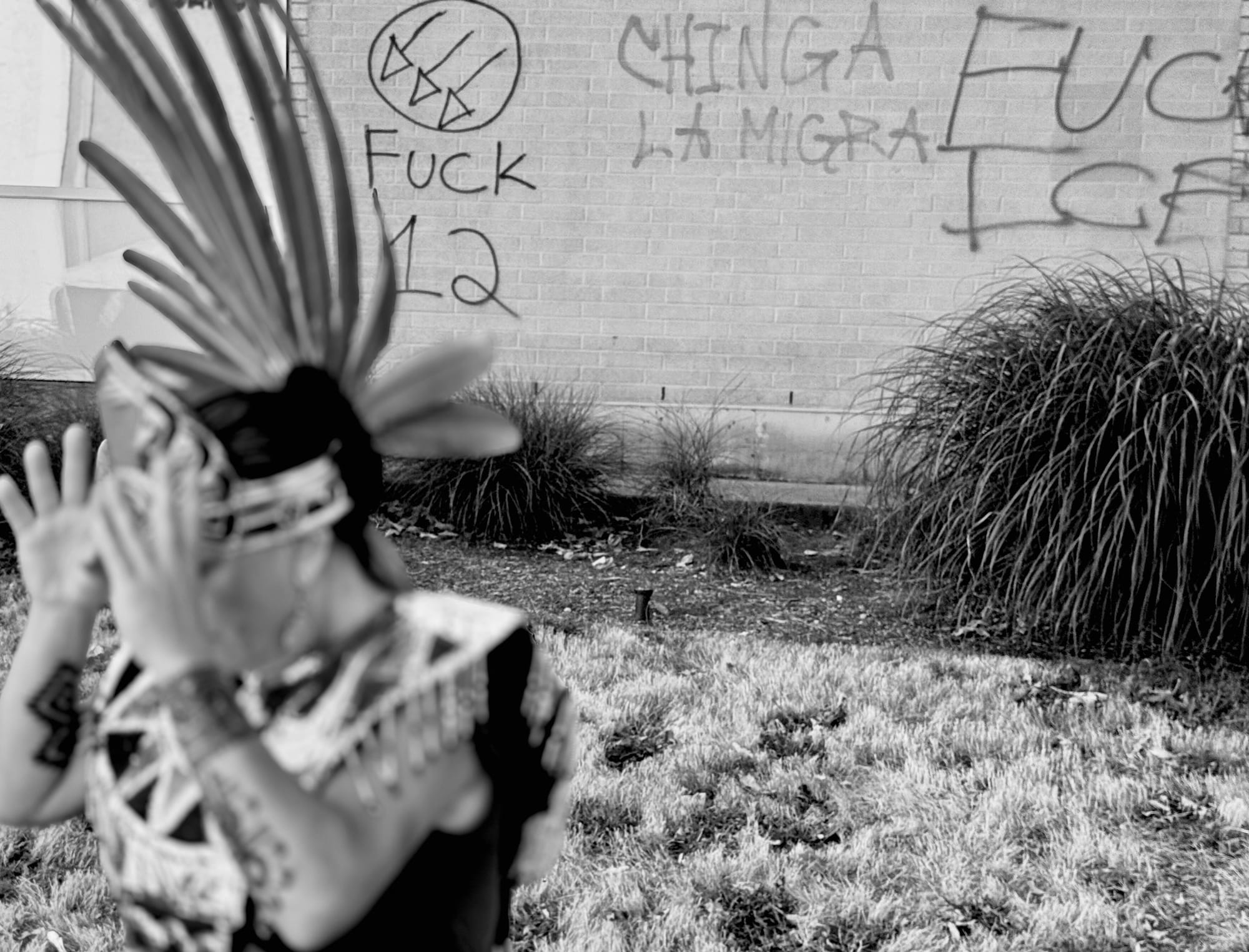 Tracy Molina outside of the ICE facility in Portland during summer of 2025. photo Is in black and white, the wall behind her says "fuck 12," "fuck ICE," and "change la migration"